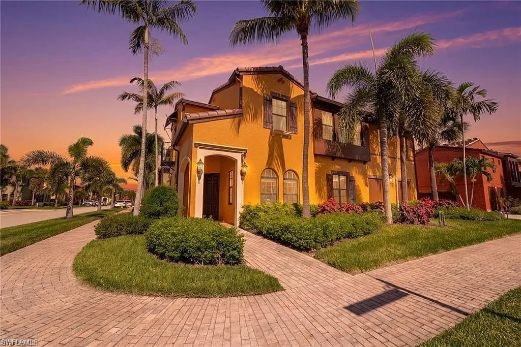 Sunset over the Mediterranean-style exterior of the home, framed by palms